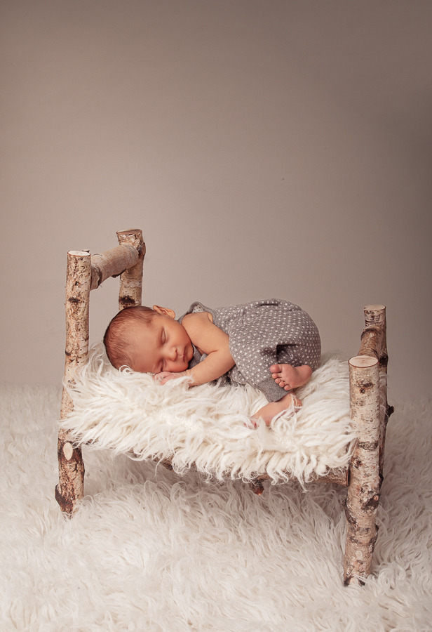 Babyfotografie in einem süßen Holzbettchen